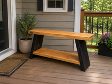Load image into Gallery viewer, A rustic wooden entryway bench with a natural live-edge top and shelf, supported by dark stained A-frame legs, shown on a wooden porch.