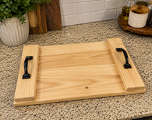 Load image into Gallery viewer, A rectangular wooden serving tray with open sides and black metal handles, placed on a speckled granite countertop in a kitchen setting.
